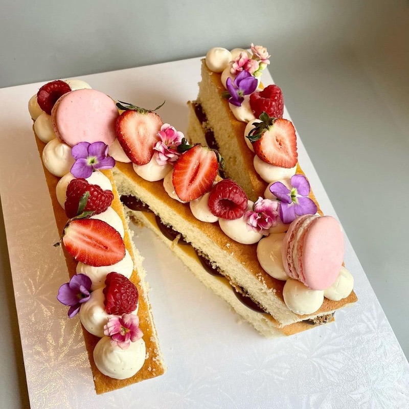 Letter cake decorated with fresh berries, macarons and flowers